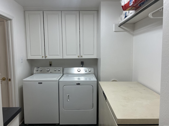 clothes washing area with cabinets and washing machine and dryer