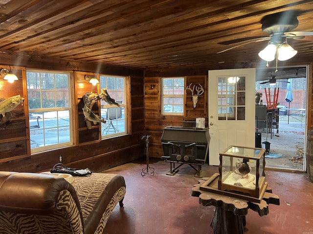 sitting room featuring ceiling fan, wood walls, a wood stove, and wooden ceiling