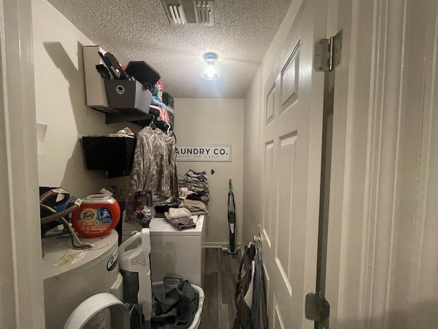 clothes washing area featuring hardwood / wood-style floors, washing machine and clothes dryer, and a textured ceiling