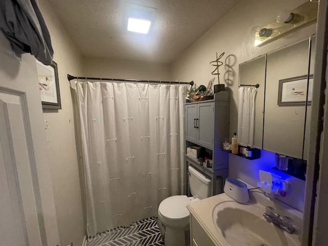 bathroom with vanity, toilet, curtained shower, and a textured ceiling