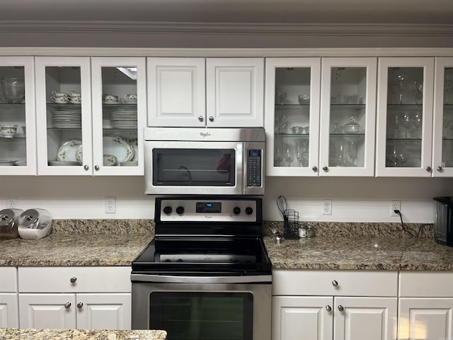 kitchen featuring dark stone countertops, ornamental molding, appliances with stainless steel finishes, and white cabinets