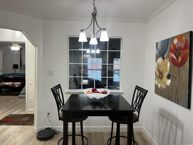 dining space with hardwood / wood-style floors, crown molding, and ceiling fan with notable chandelier