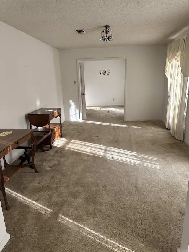 interior space featuring carpet, a textured ceiling, and an inviting chandelier