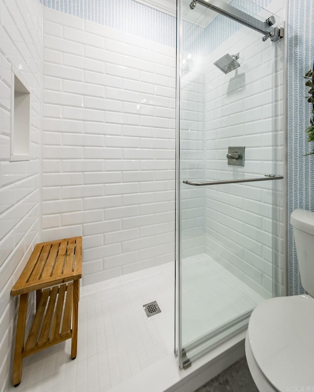 bathroom featuring tile patterned floors, toilet, and a shower with door