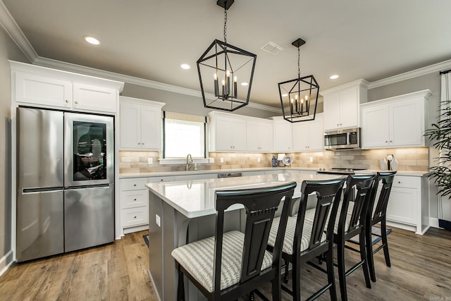 kitchen with a kitchen bar, white cabinetry, a kitchen island, and stainless steel appliances