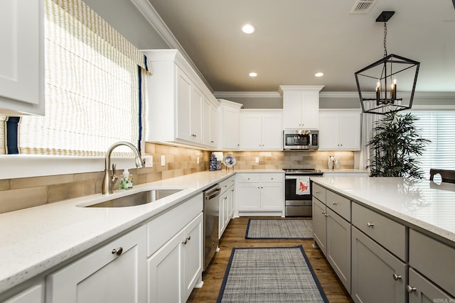 kitchen with light stone countertops, sink, gray cabinets, white cabinets, and appliances with stainless steel finishes