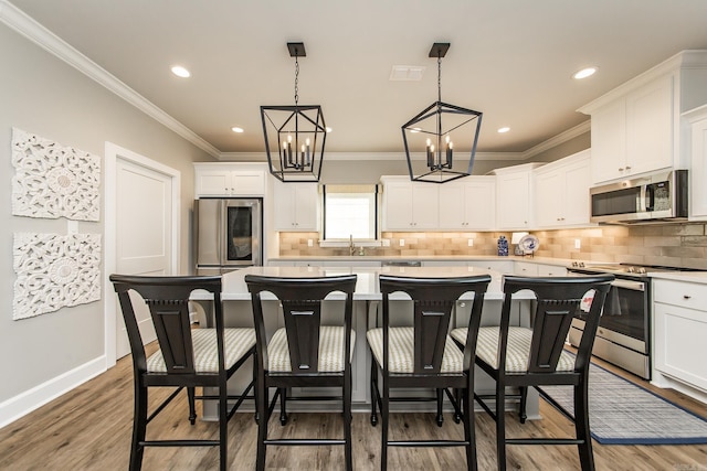 kitchen featuring a kitchen bar, stainless steel appliances, pendant lighting, white cabinets, and a kitchen island