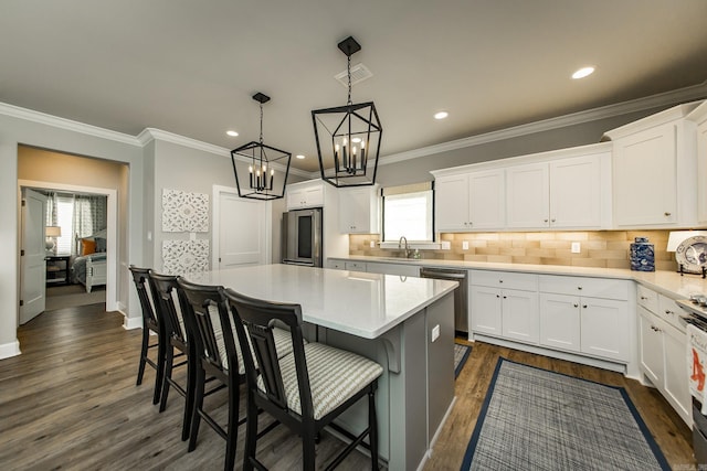 kitchen with white cabinets, decorative backsplash, a center island, and stainless steel appliances