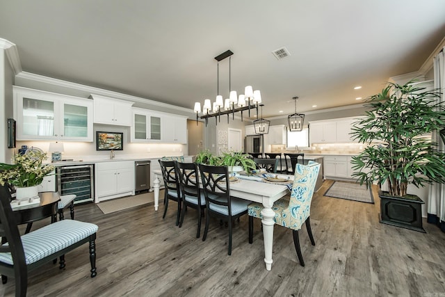 dining space featuring wine cooler, hardwood / wood-style floors, and ornamental molding