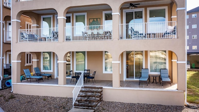 rear view of house with ceiling fan, a balcony, and a patio