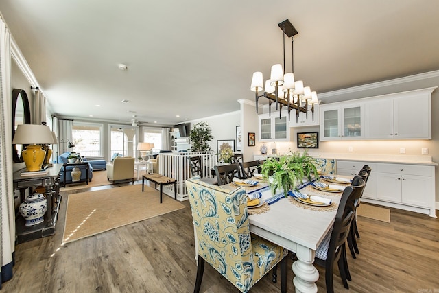 dining area with dark hardwood / wood-style floors, crown molding, and an inviting chandelier