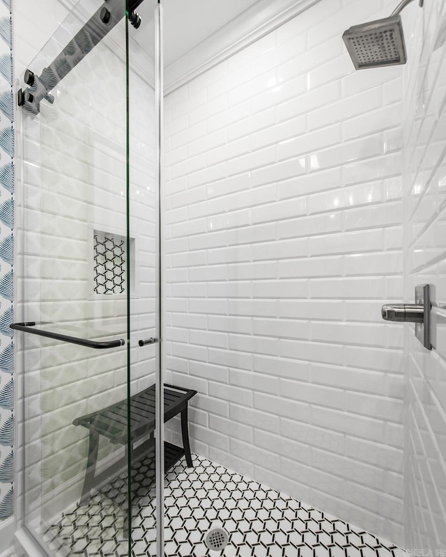 bathroom with a shower with shower door and ornamental molding