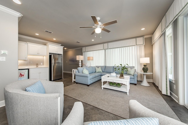 living room with ceiling fan, ornamental molding, and sink