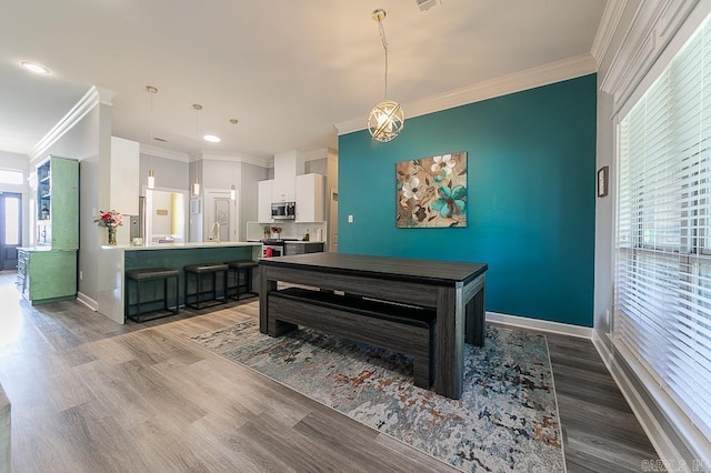 dining room featuring wood-type flooring, ornamental molding, sink, and a wealth of natural light