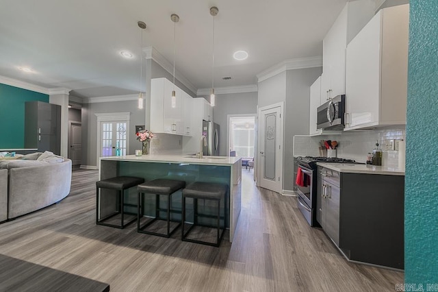 kitchen featuring a kitchen bar, white cabinets, decorative light fixtures, and appliances with stainless steel finishes