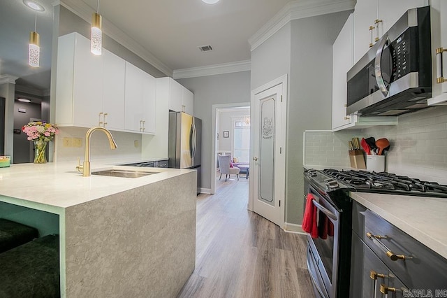 kitchen featuring white cabinetry, sink, hanging light fixtures, stainless steel appliances, and crown molding