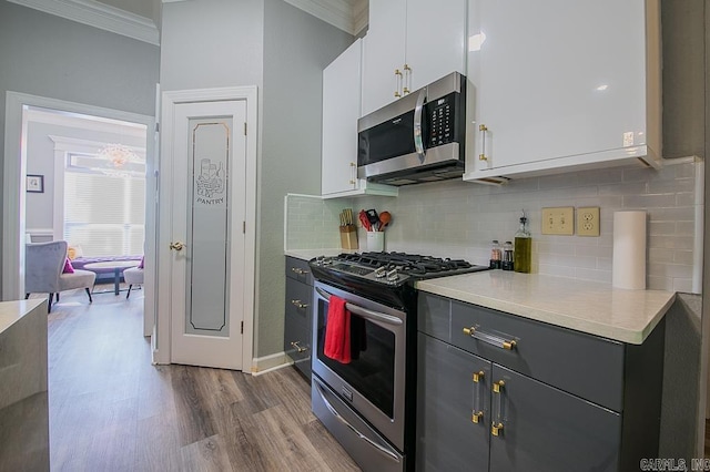 kitchen featuring hardwood / wood-style floors, decorative backsplash, gray cabinets, white cabinetry, and stainless steel appliances