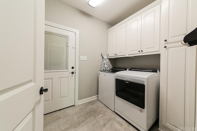 clothes washing area with cabinets and washing machine and clothes dryer