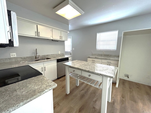 kitchen with white cabinets, a center island, stainless steel dishwasher, and sink