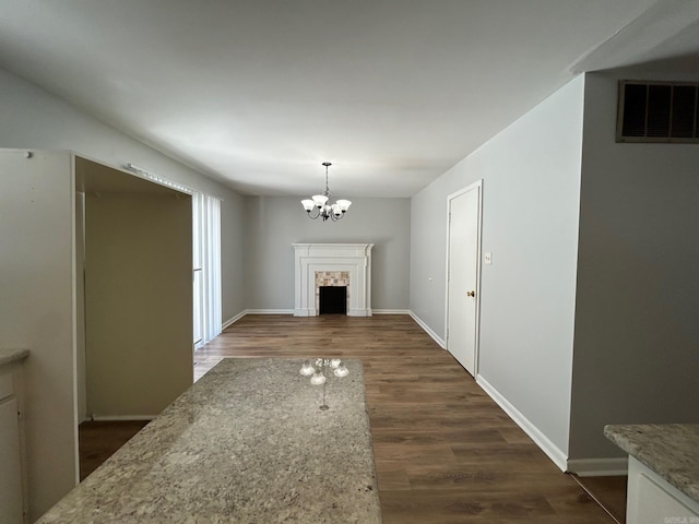 unfurnished living room featuring dark hardwood / wood-style flooring, a tile fireplace, and a chandelier