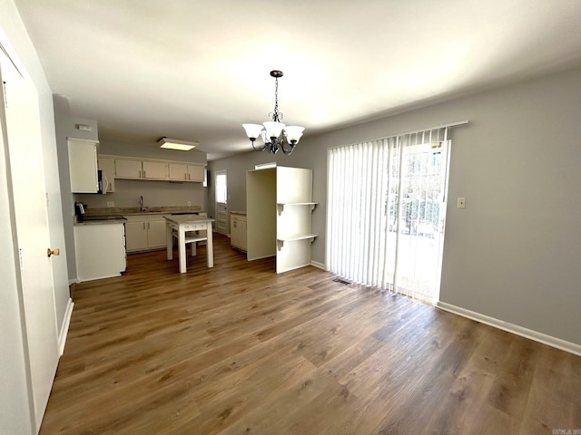 kitchen featuring dark hardwood / wood-style flooring, white cabinets, sink, pendant lighting, and a chandelier