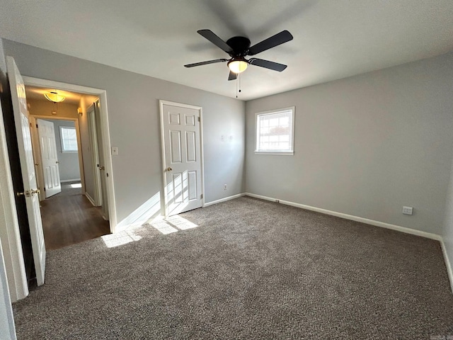 unfurnished bedroom featuring dark colored carpet, ceiling fan, and multiple windows