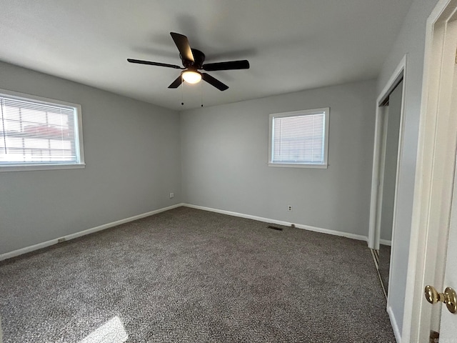 unfurnished bedroom featuring multiple windows, ceiling fan, a closet, and dark carpet