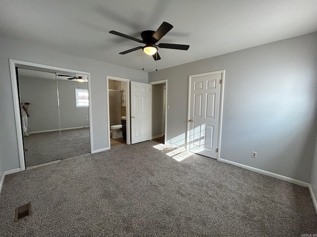 unfurnished bedroom with dark colored carpet, ceiling fan, and connected bathroom