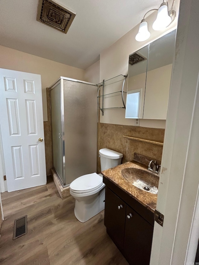 bathroom featuring hardwood / wood-style floors, vanity, toilet, and a shower with shower door