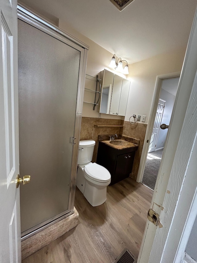 bathroom with hardwood / wood-style floors, vanity, toilet, and walk in shower