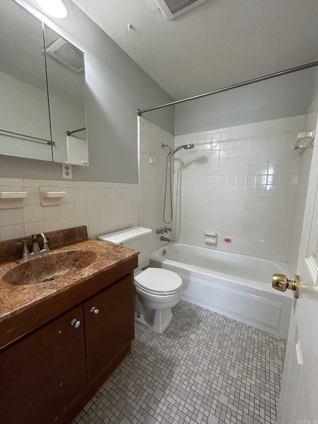 full bathroom with tile patterned floors, toilet, tile walls, and tiled shower / bath