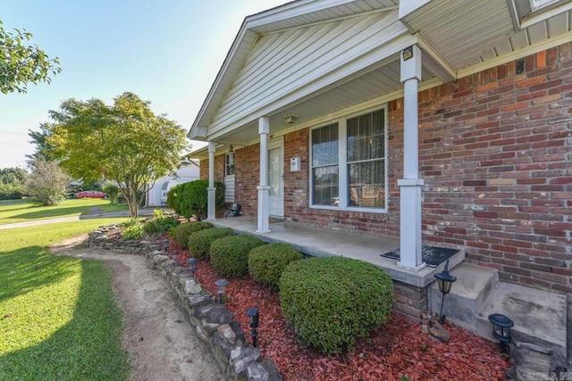 view of exterior entry featuring a porch and a lawn