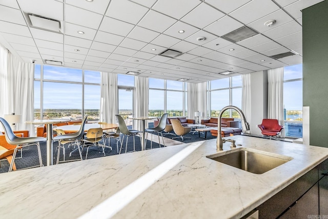 kitchen with a paneled ceiling, expansive windows, a water view, and sink