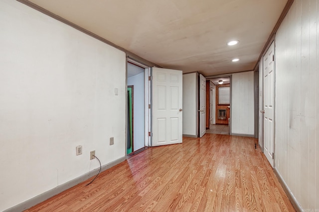 unfurnished bedroom featuring wood walls, ornamental molding, and light wood-type flooring