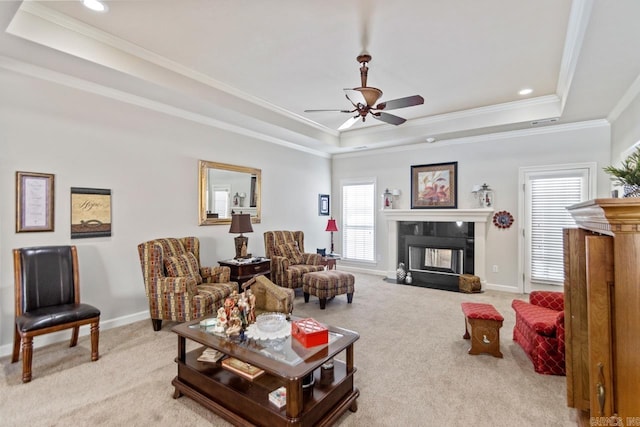 living room featuring light carpet, a tray ceiling, ceiling fan, crown molding, and a multi sided fireplace