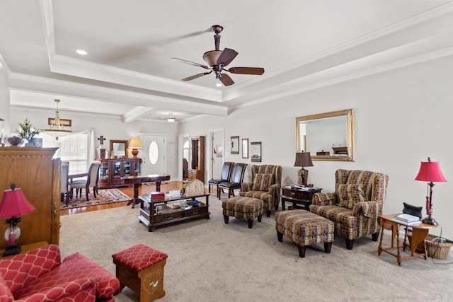 carpeted living room with a tray ceiling, ceiling fan, and ornamental molding