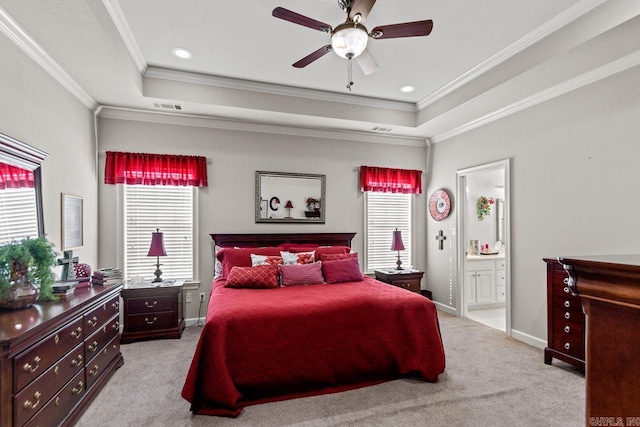 carpeted bedroom with a tray ceiling, ensuite bath, ceiling fan, and ornamental molding