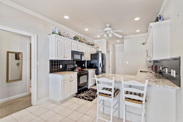 kitchen featuring kitchen peninsula, decorative backsplash, sink, black appliances, and white cabinetry