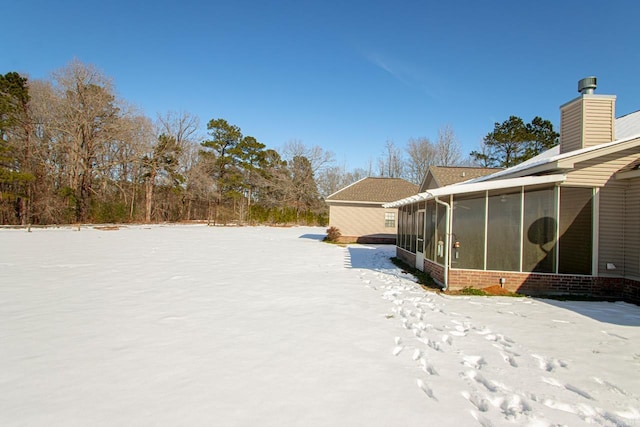 yard layered in snow with a sunroom