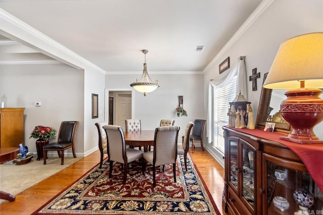 dining room with light wood-type flooring and crown molding