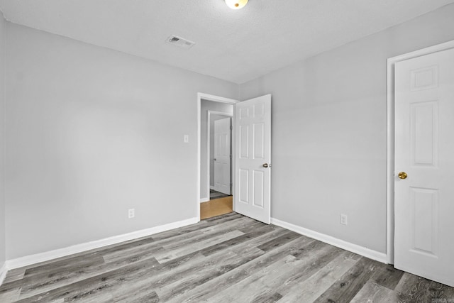 empty room with hardwood / wood-style floors and a textured ceiling