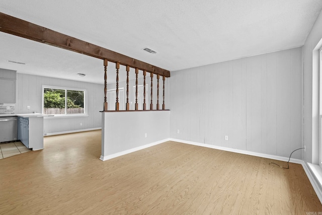 unfurnished room with beamed ceiling, a textured ceiling, and light hardwood / wood-style flooring