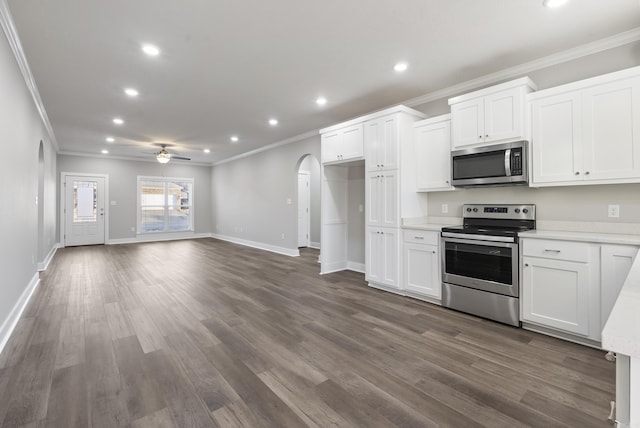 kitchen with white cabinetry, ceiling fan, stainless steel appliances, dark hardwood / wood-style flooring, and ornamental molding