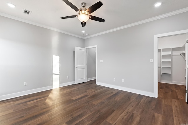 unfurnished bedroom featuring a walk in closet, crown molding, ceiling fan, dark hardwood / wood-style flooring, and a closet