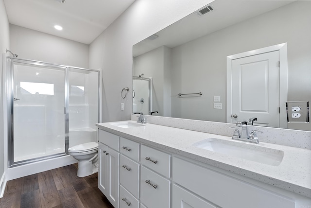 bathroom featuring vanity, wood-type flooring, a shower with shower door, and toilet