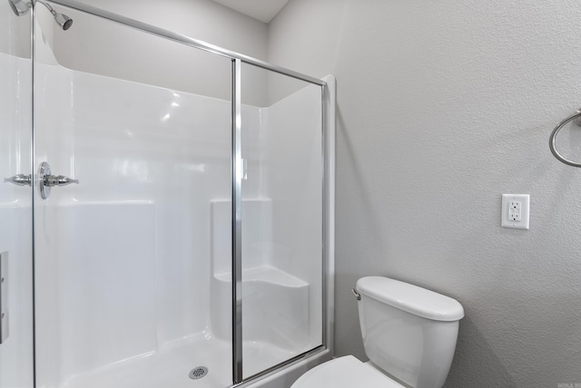 bathroom featuring toilet and a shower with door