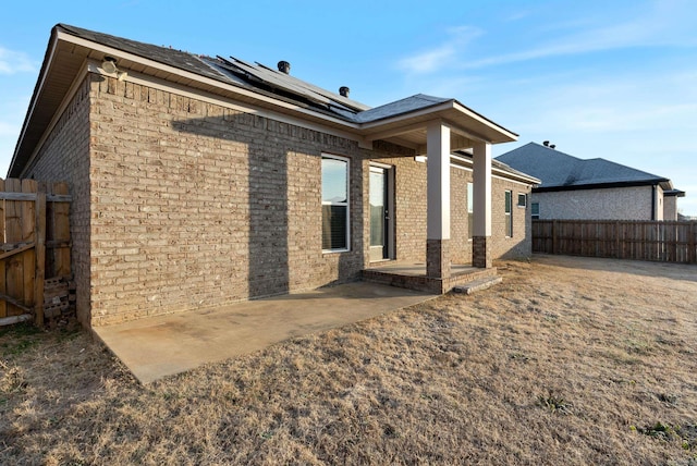 rear view of property with solar panels and a patio