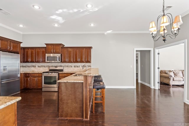 kitchen with a kitchen breakfast bar, crown molding, decorative backsplash, stainless steel appliances, and a chandelier