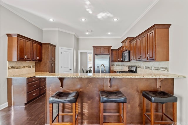 kitchen with crown molding, decorative backsplash, dark hardwood / wood-style floors, appliances with stainless steel finishes, and kitchen peninsula