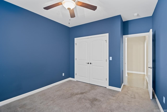 unfurnished bedroom featuring ceiling fan, a closet, and light colored carpet